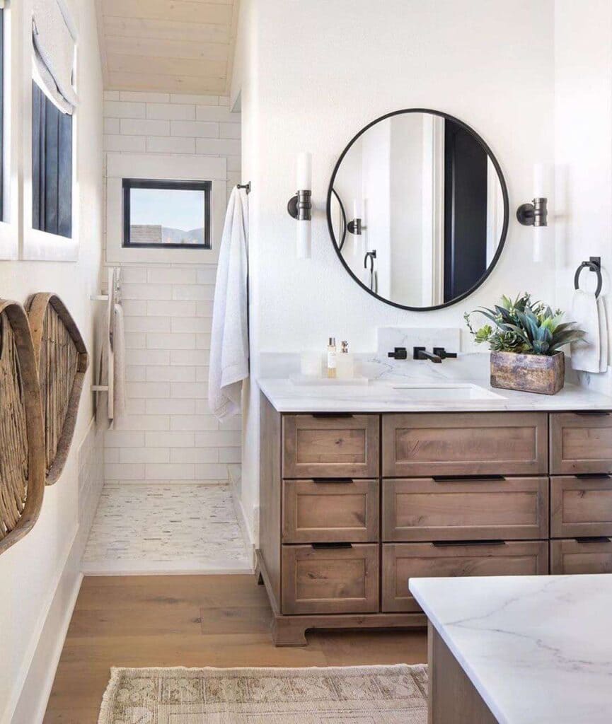 A bathroom view with wooden drawers and circular mirror giving a modern a rusty look