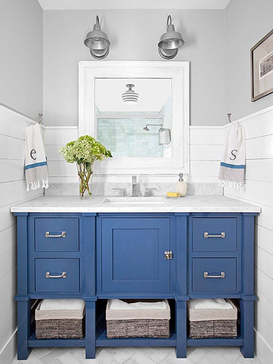 A small bathroom with blue cabinets and a lighthouse look