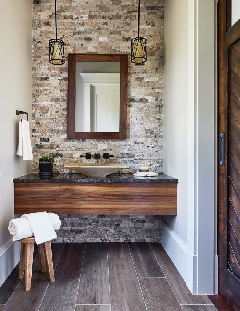 A view of a bathroom wall having stone with a wooden sink in contrast