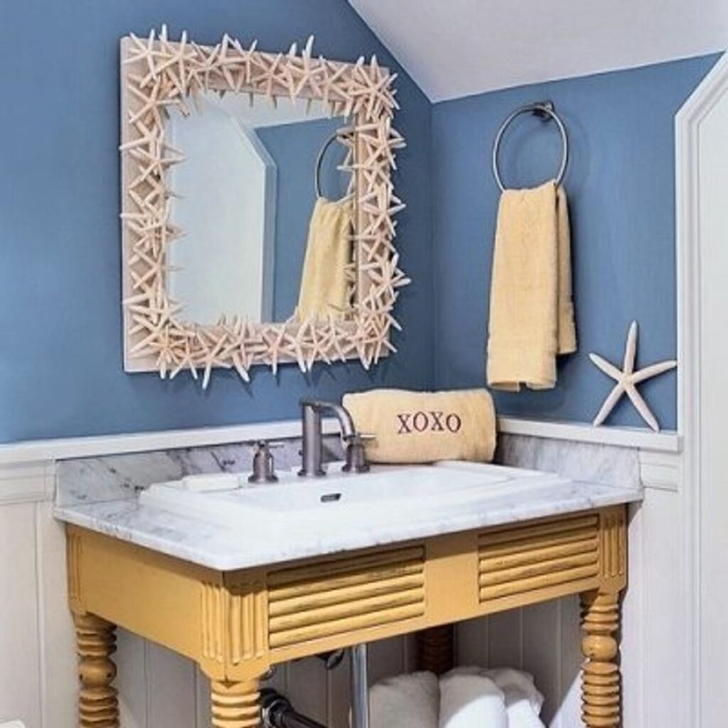 A view of a bathroom with sea shells accessories a mirror with sea shell border above the sink