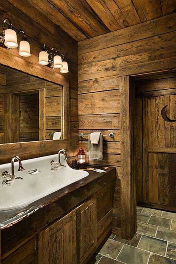 A view of a small rustic bathroom with wooden interior and a sink