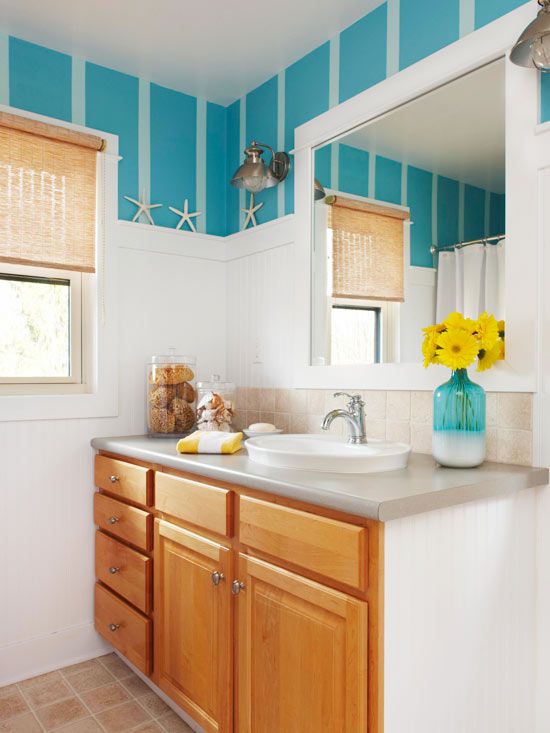 A view of a white and blue bathroom with wooden cabinets and a lake front look