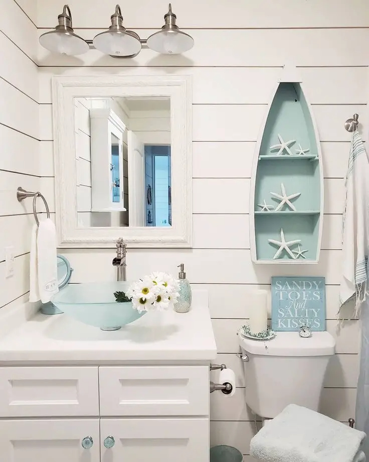 A view of a white bathroom space with a ship shaped storage rack with starfish inside