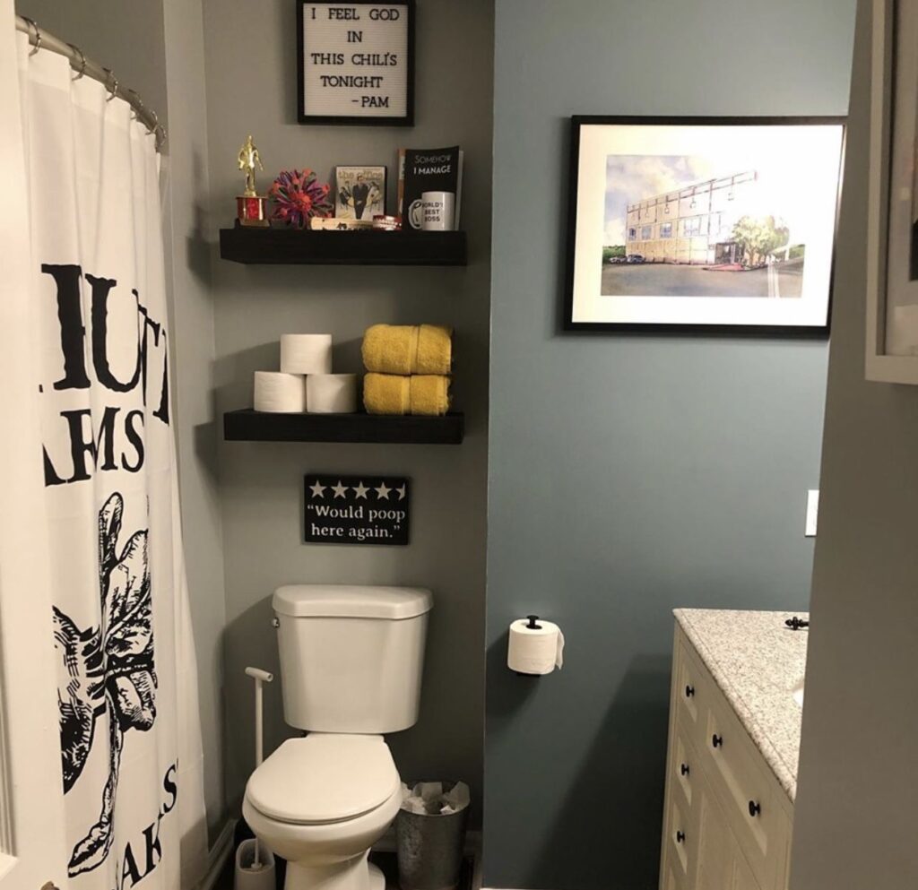 black and white themed office bathroom with toileteries on floating shelves