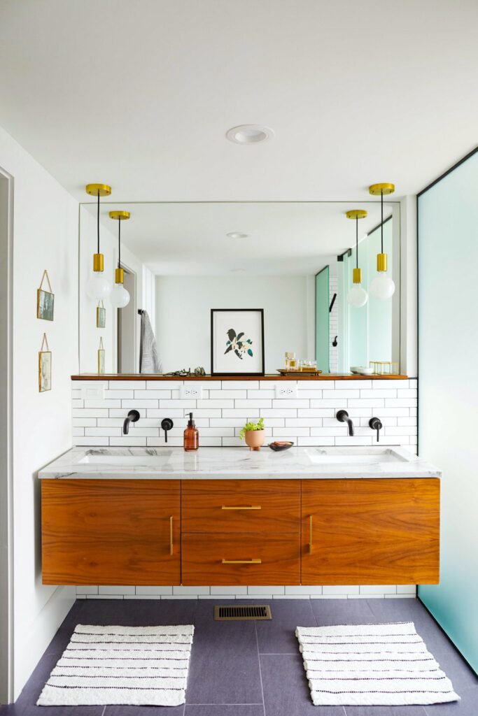 brown colored floating vanity in a bathroom a large mirror lighting fixtures