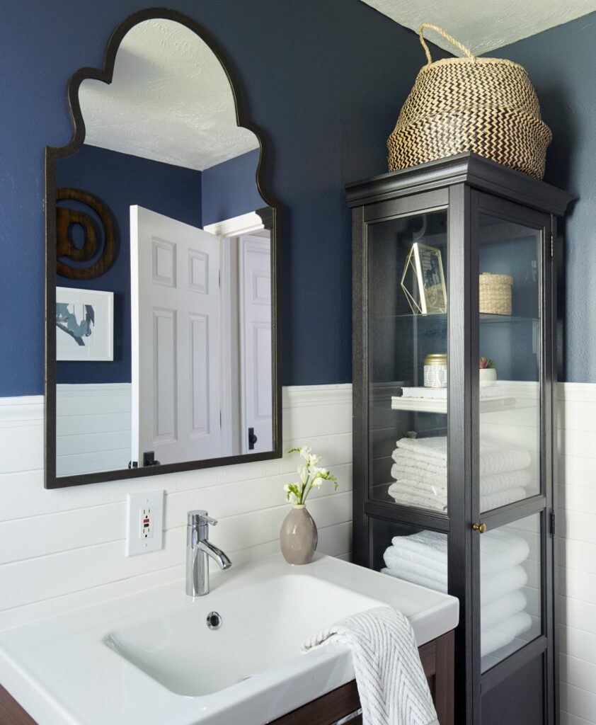 vertical shelves in bathroom towels and other items organized in it a mirror and decorative piece placed along the sink