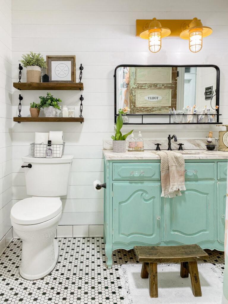 vintage blue colored vanity in a bathroom flaoting shelves with different items placed on them a mirror and stool