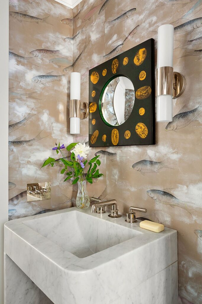 wallpaper with fish art on it in the bathroom wirh small mirror lighting fixtures and a sink
