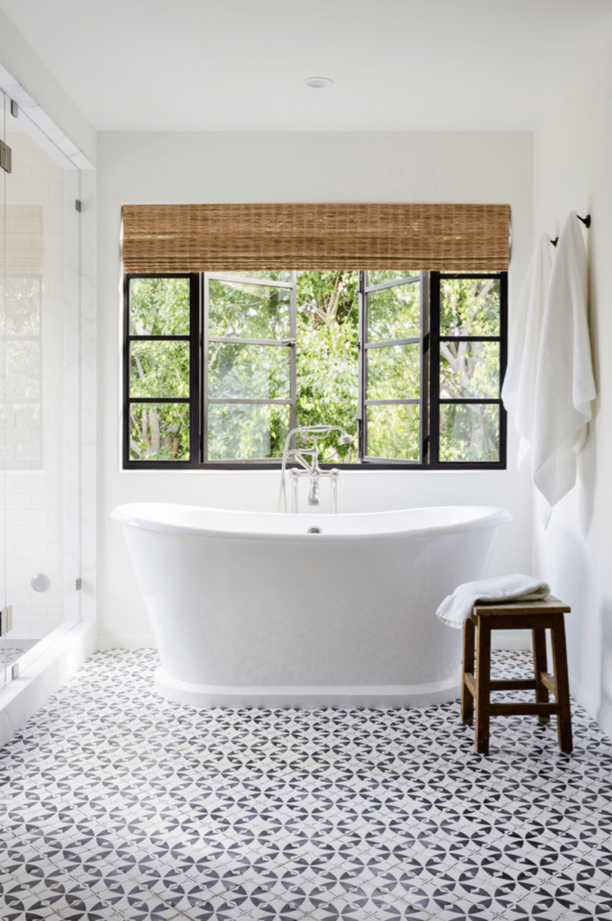 A view of a bathroom with a white tub and patterned white and black tiles
