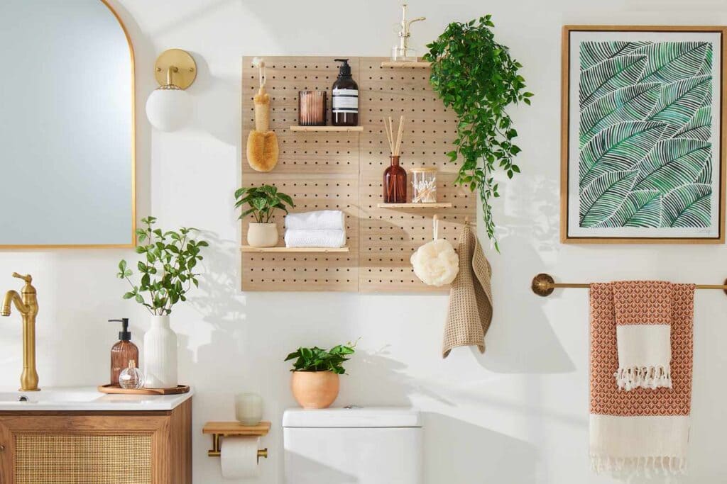 clutter free space in a bathroom with toiletries hung on shelves plants shampoos towel and art piece hung on wall