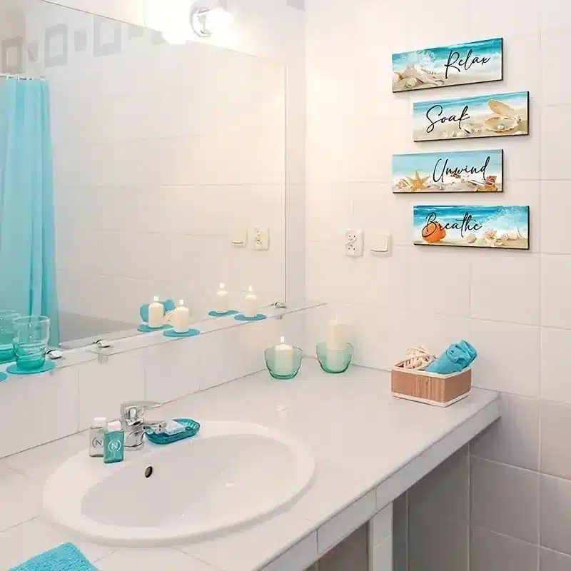 beachy paintings hung on wall of bathroom candles lit a sink