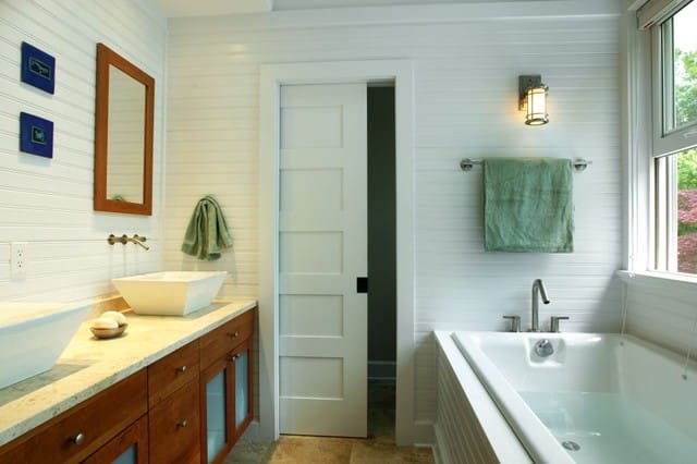 bathroom pocket door bathtub and two sinks