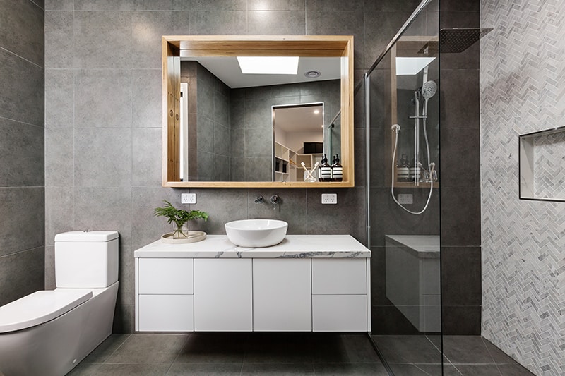 compact and neat bathroom with white vanity mirror and toilet