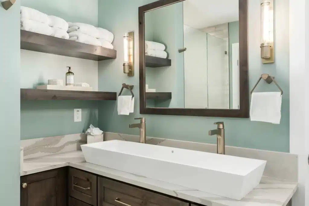 mirror and L shaped counter in bathroom towels placed on shelves