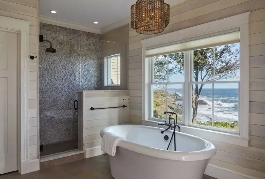 pebble floor tiles in bathroom a white bathtub a large window