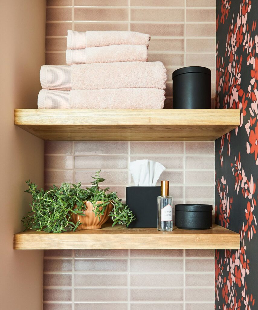 mirror and L shaped counter in bathroom towels placed on shelves