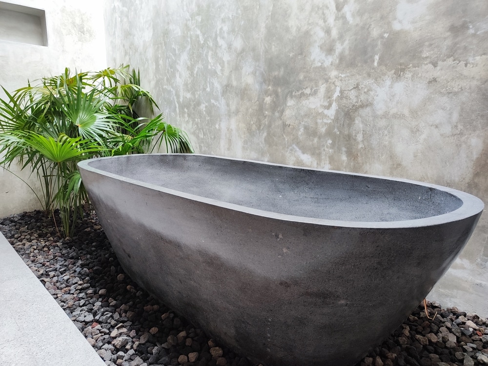 A Dark Gray Terrazzo Bathtub In A Tropical themed Villa Bathroom