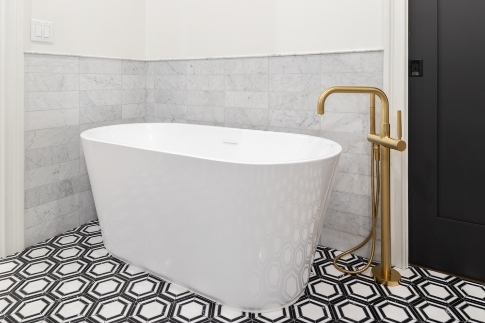 A Freestanding Tub With A Gold Faucet Black And White