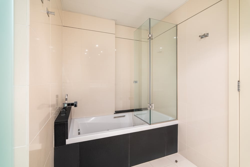 Bathroom with a white bathtub for bathing and relaxation in glossy black marble tiles.