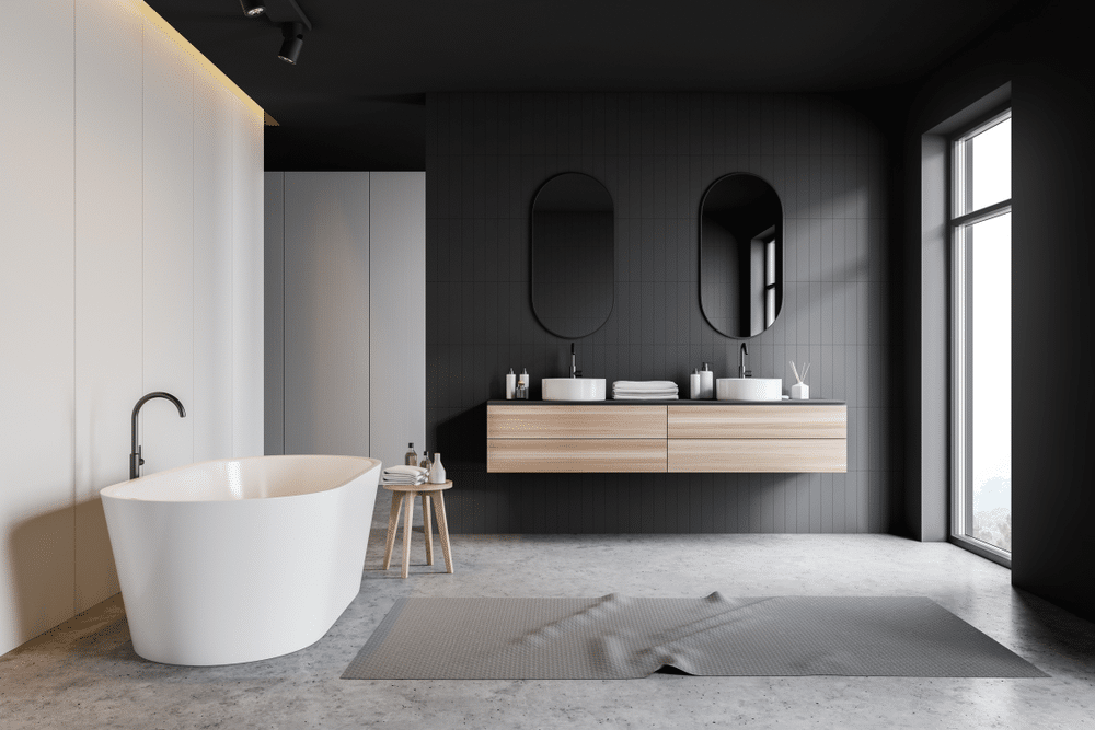 Interior of stylish bathroom with gray tile and white walls concrete floor double sink standing on wooden countertop comfortable white bathtub and large window