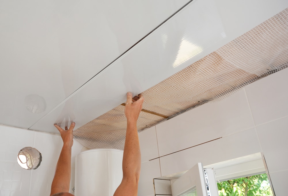 a person is fixing the tiles in the bathroom ceiling